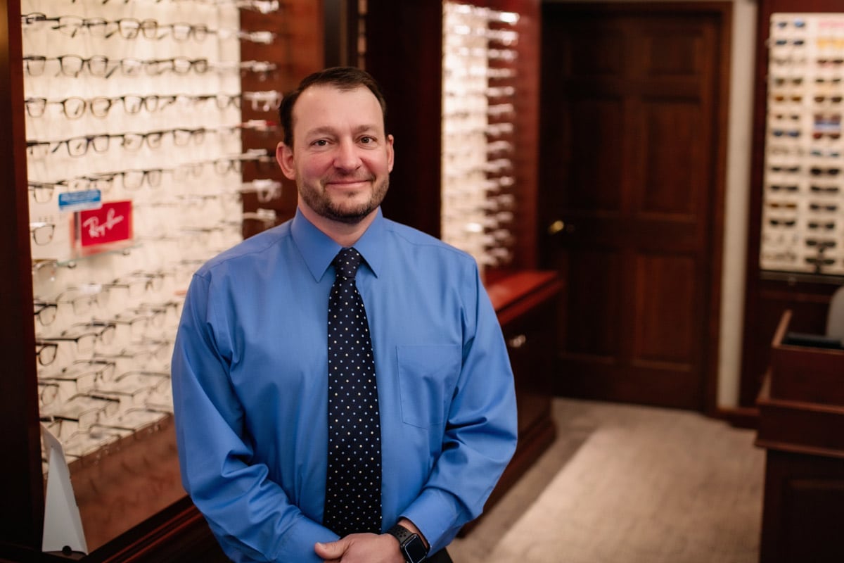 Dr. Cory Lindenman standing in front of eyeglasses display